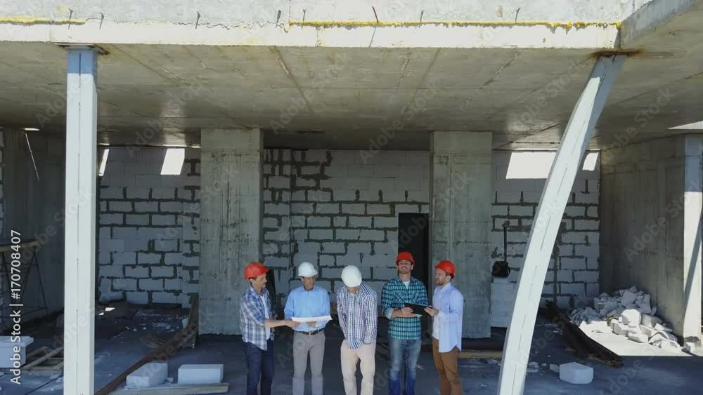 Poster aerial shot of builders team on construction site discussing plan of project with architect and cont