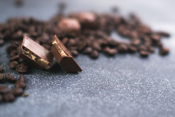 Coffee beans and tiles of dark chocolate on a dark matte background.