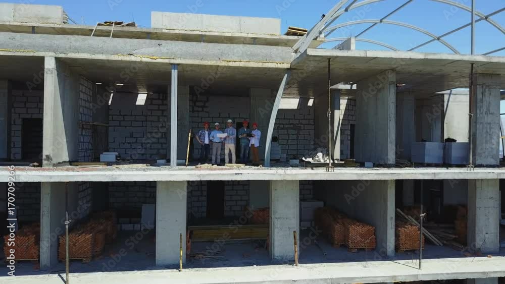 Poster aerial shot of builders team on construction site discussing plan of project with architect and cont