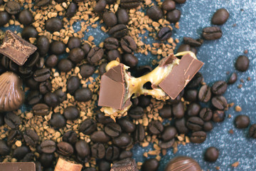 Coffee beans and tiles of dark chocolate on a dark matte background.