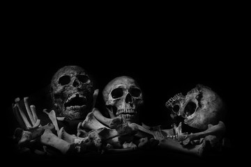 Awesome pile of skull human and bone on wooden, black cloth background. Still Life style, selective focus,