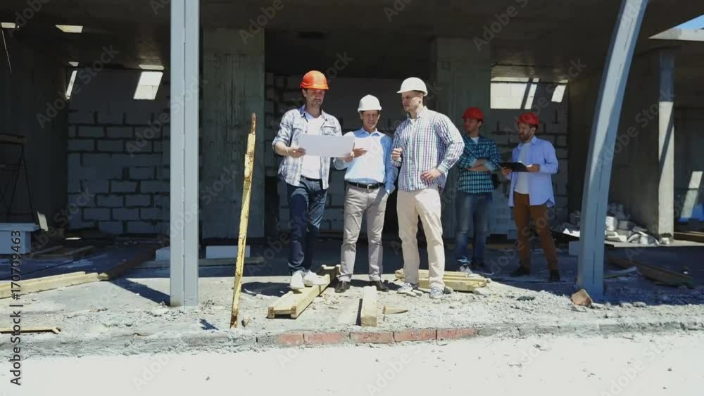 Poster aerial shot of builders team on construction site discussing plan of project with architect and cont