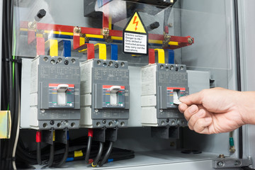 Hand of Engineer turning on switch in the electrical cabinet at control room
