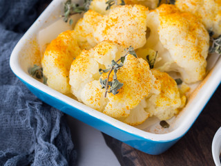 Baked cauliflower with turmeric and marjoram on rustic background. Lunch with vegetables