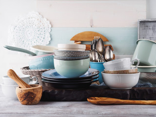 Ceramic and enamel crockery tableware on wooden background. Pastel vintage colors