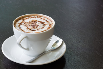 cup of coffee with spider design on black wood table