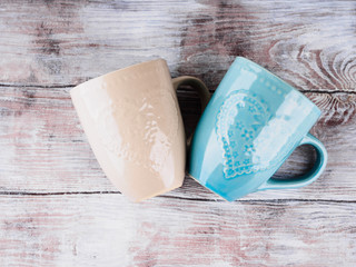Two ceramic cups with hearts on wooden background. Vintage pastel colors