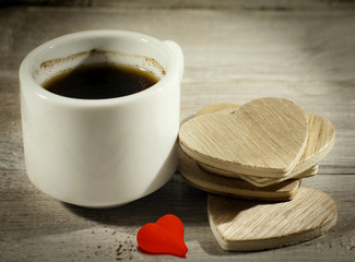 Close up cup of coffee with wooden hearts and red heart