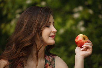 A young beautiful woman looking at a ripe apple 