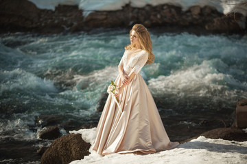 Beautiful young girl in a chic dress in the nature next to the river