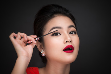 Obraz premium Make-up and cosmetics concept. Asian woman doing her makeup eyelashes black mascara.