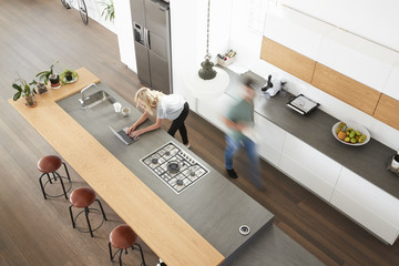 Overhead View Of Busy Couple In Modern Kitchen