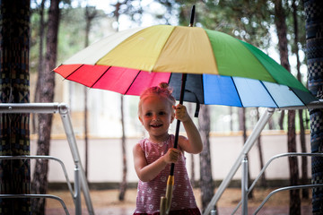 Cute blonde child smiling and holding colorful umbrella
