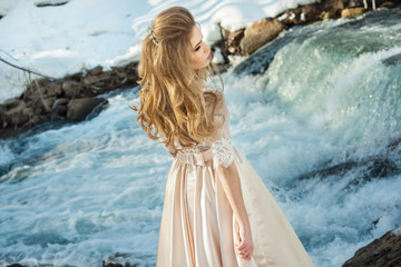 Beautiful young girl in a chic dress in the nature next to the river