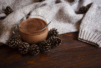 Autumn lifestyle - hot chocolate on tray, warm sweater, candle and cones, rustic wood background