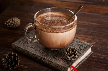 Fotobehang Cup of hot chocolate on notebook and old wooden table with cones © Ekaterina
