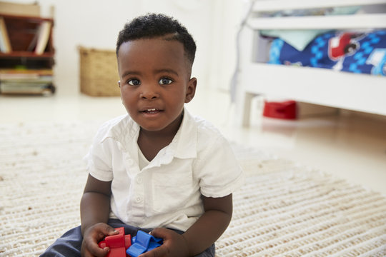 Portrait Of Happy Boy Playing With Toys In Playroom