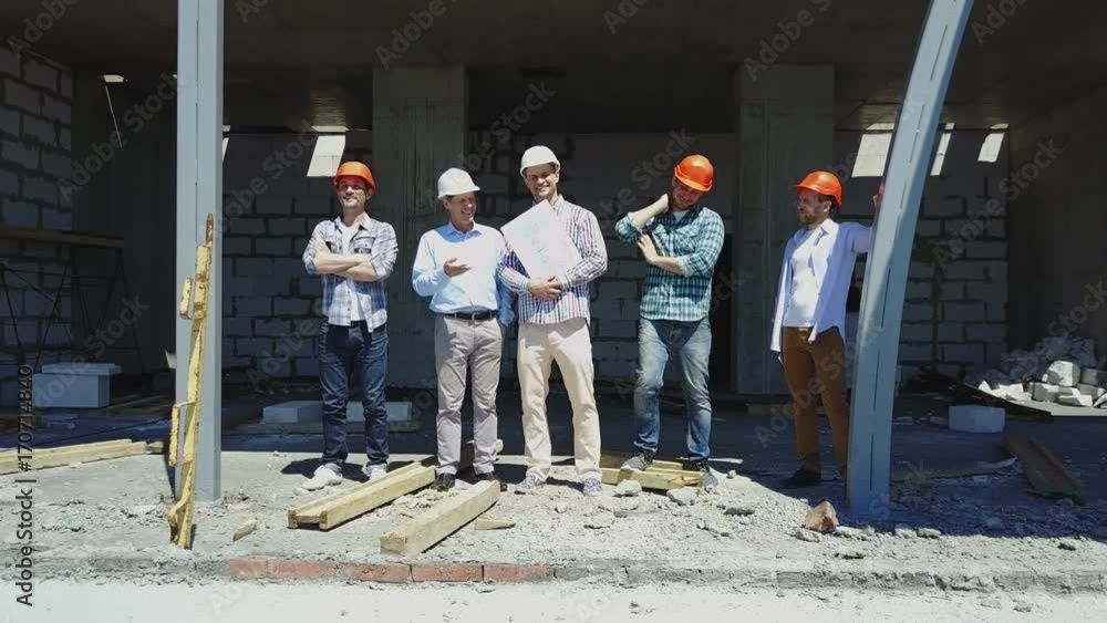 Poster aerial shot of builders team on construction site discussing plan of project with architect and cont