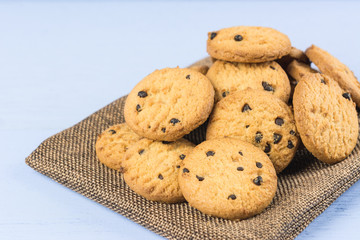 pile of chocolate butter cookies on calico fabric with light blue wooden background