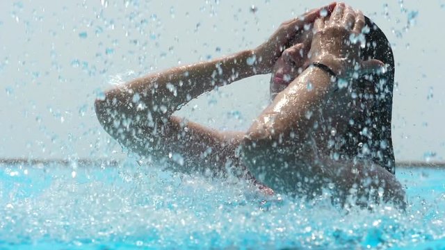 Woman under swimming pool waterfall. Slow motion.

