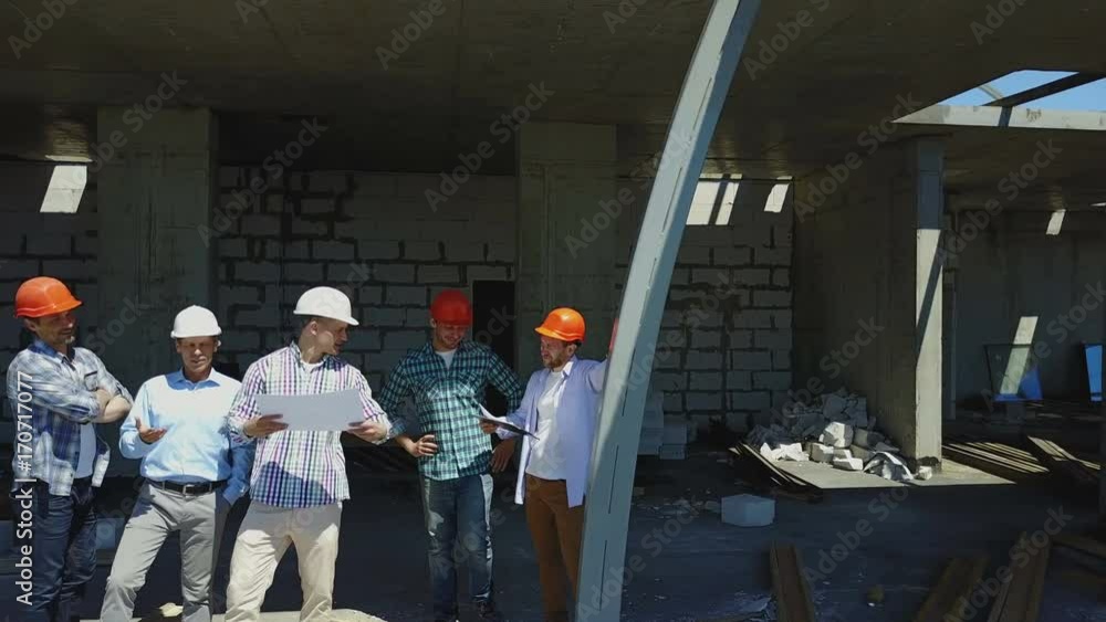 Poster aerial shot of builders team on construction site discussing plan of project with architect and cont