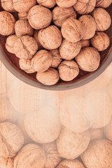 whole walnuts in a clay plate on a white wooden background. Rustic style. Background with a print of walnuts
