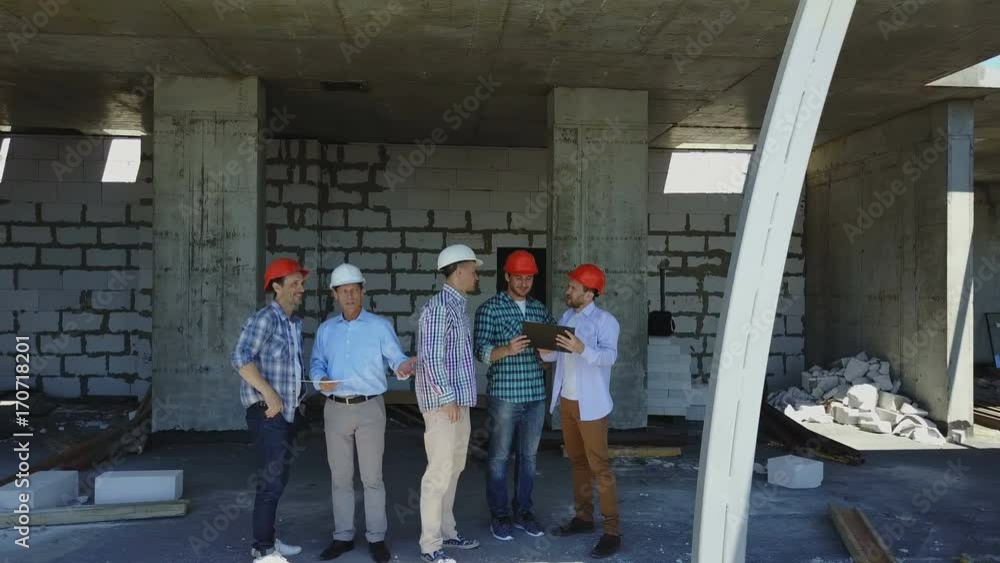 Poster aerial shot of builders team on construction site discussing plan of project with architect and cont