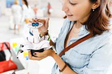 Young adult woman looking at the toy robot at the exhibition