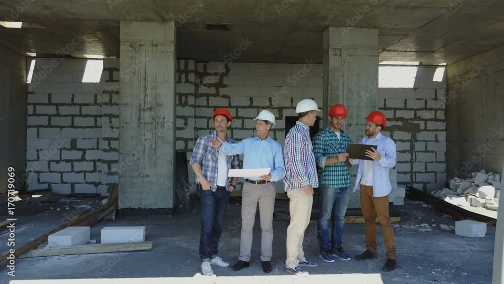 Poster aerial shot of builders team on construction site discussing plan of project with architect and cont