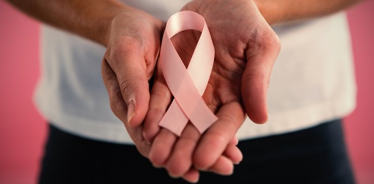 Mid section of woman holding pink ribbon
