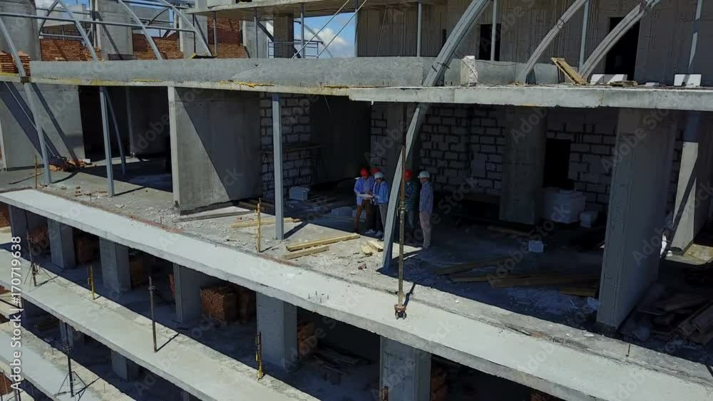 Poster aerial shot of builders team on construction site discussing plan of project with architect and cont