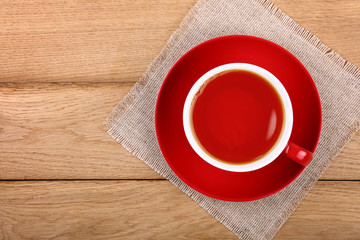 Full cup of black tea in red cup on wooden table