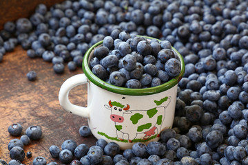 Fresh ripe blueberry in white metal mug close up