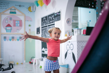 Little girl in playground. Caucasian girl playing in playroom. Looking at camera.