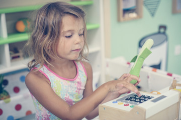 Little girl in playground. Girl playing with children cash register.