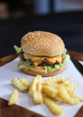 hamburger with french fries served on a wooden plate.