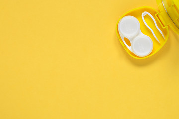 Accessories for contact lenses: container, tweezers. Yellow background.