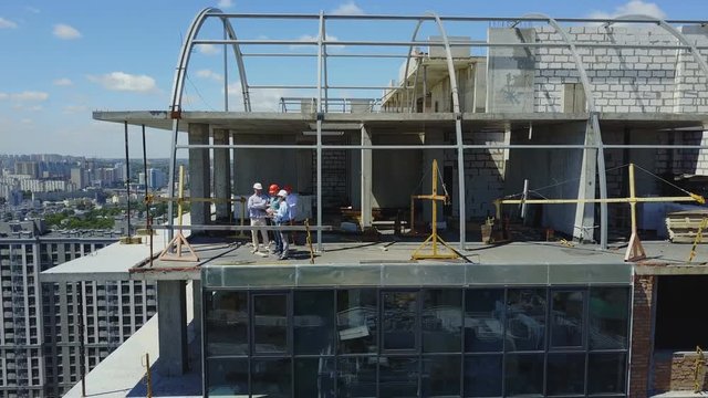 Aerial View Of Construction Site With Team Of Builders On Roof Discussing Plan Of Project Drone Shot