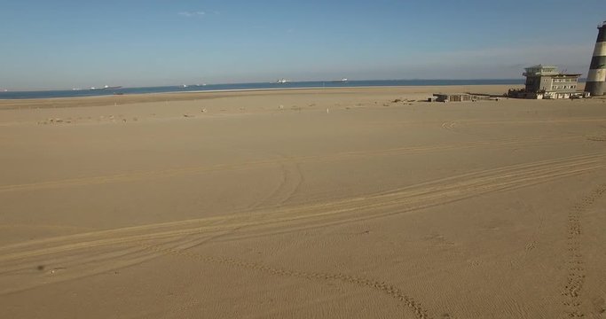 Aerial view footage of desert sand peninsula, old lighthouse and power station building on ocean seals beach, Walvis Bay lagoon view with sea background and ships at Namibia's Atlantic west coast