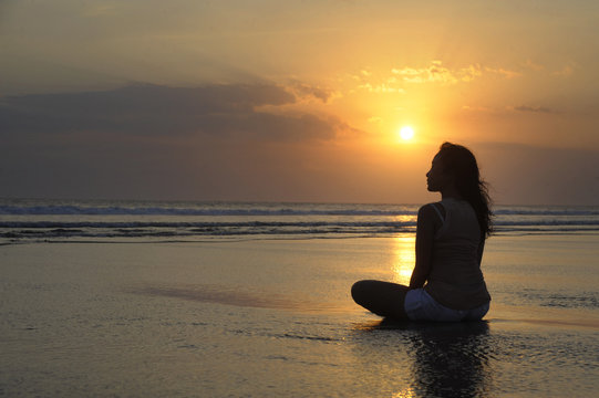 Silhouette Of Young Beautiful Asian Woman Sitting On Sand Water Free And Relaxed Looking At The Sun On Sunset Beach
