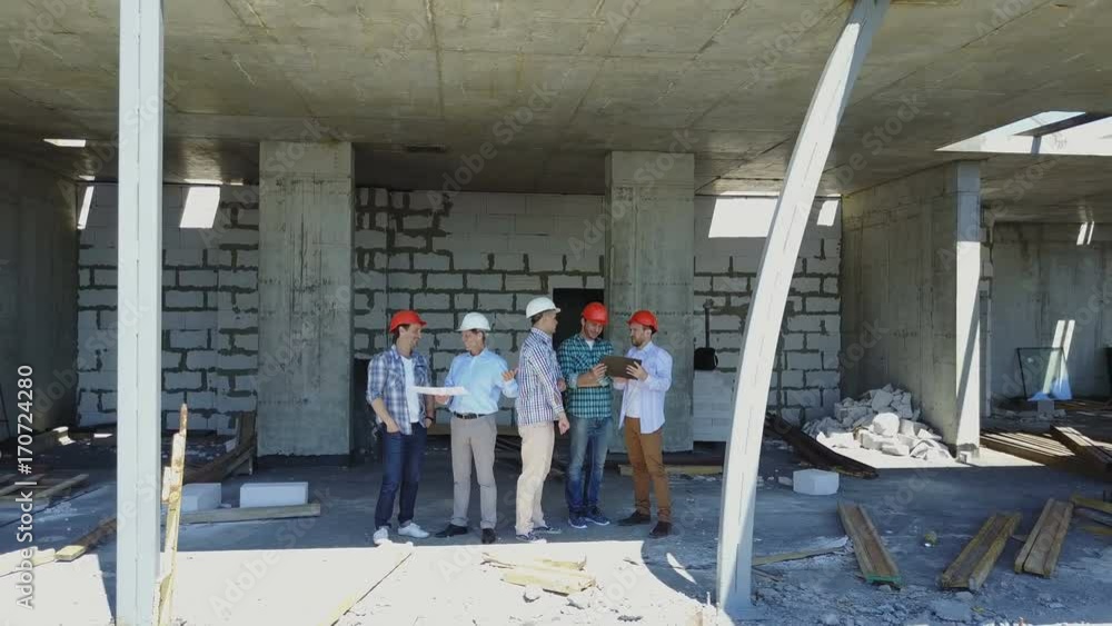 Poster aerial shot of builders team on construction site discussing plan of project with architect and cont