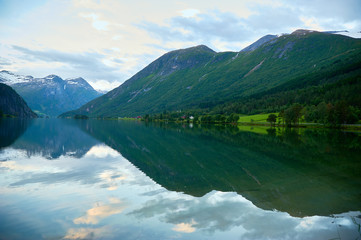Naklejka na ściany i meble Reflection of green mountains and sky in the lake