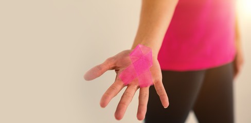 Mid section of woman showing pink breast cancer awareness ribbon