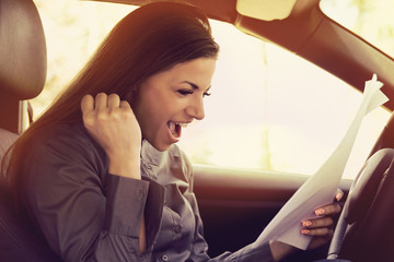 Young excited woman inside new car reading documents