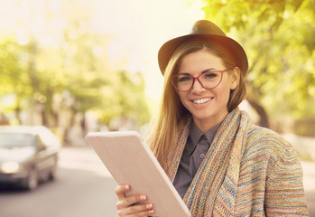 happy woman in glasses with tablet computer in a city