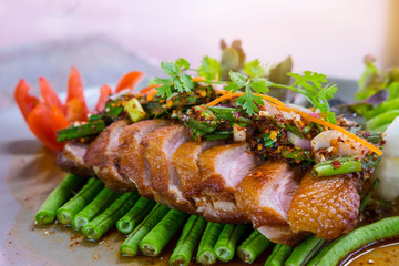 Spicy roast duck meat salad with vegetables and tomato in white plate on wooden table