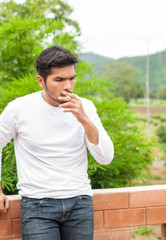 Closed up ,Bearded Asian Handsome man smoke cigarette making seriously decision something,outdoor office,Health and lifestyle concept,vintage tone