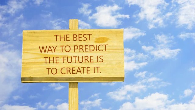 The best way to predict the future is to create it. Words on a wooden sign against time lapse clouds in the blue sky.