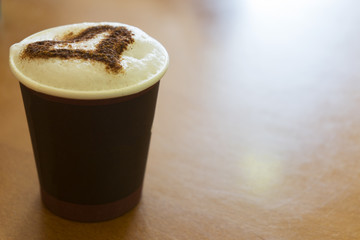 A cup of cappuccino coffee on the wooden table