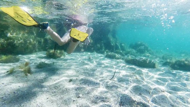 Little girl with fins, mask and snorkel swimming in the sea, gopro underwater footage